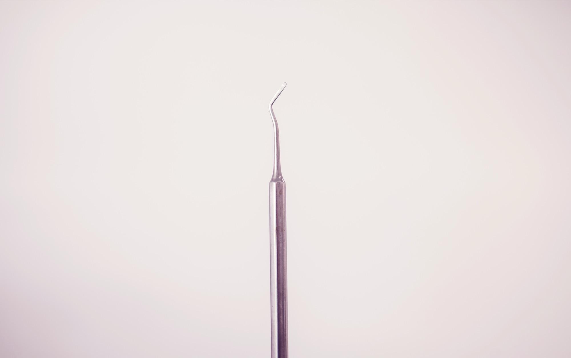 Enkel dental sonde mot en lys, varm bakgrunn