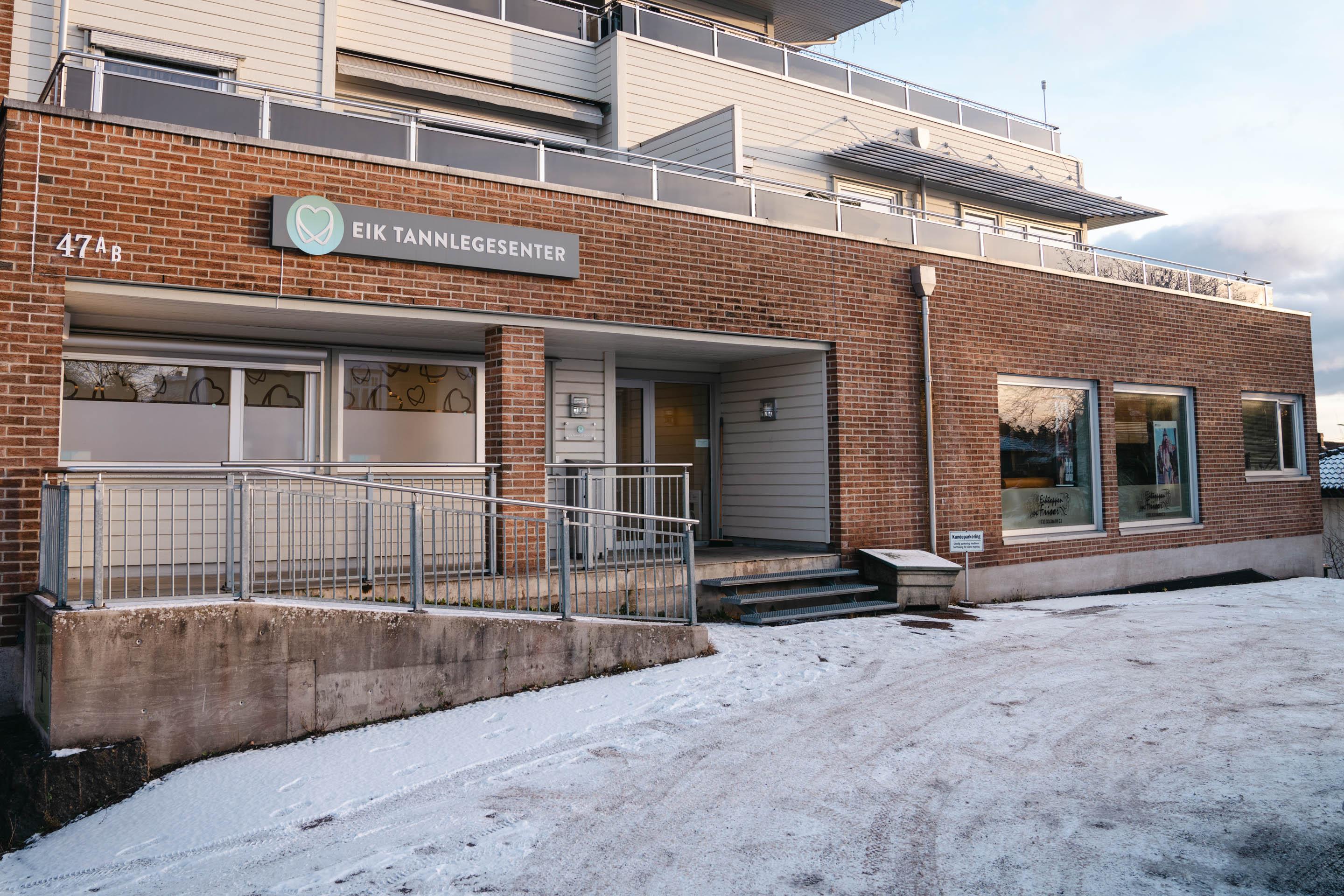 Fasaden til Eik Tannlegesenter i Eikveien 47B, med skiltet over inngangen og gratis parkering rett utenfor døren.