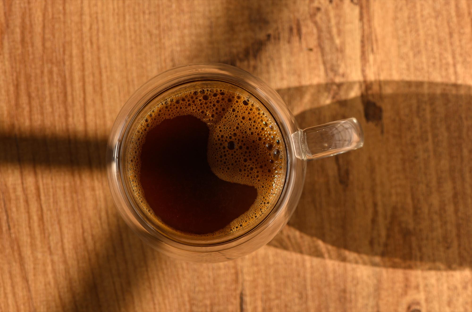 Kopp med nytraktet kaffe på et trebord, sett ovenfra