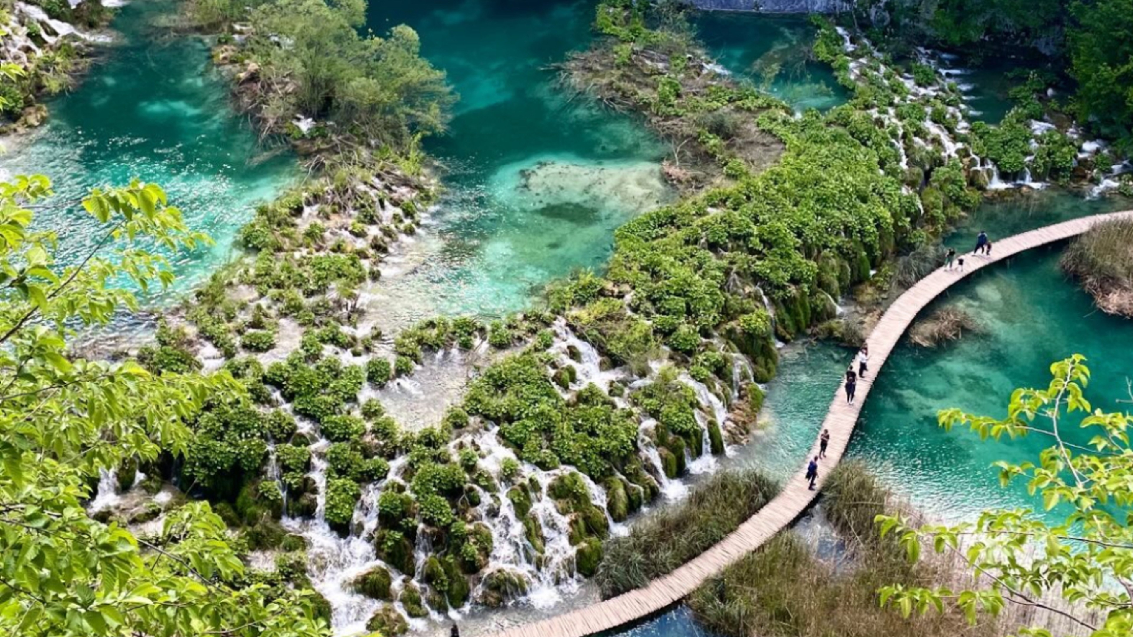 A picture of plitvice lakes national park in Croatia showing a blue/green lake next to a cliff.