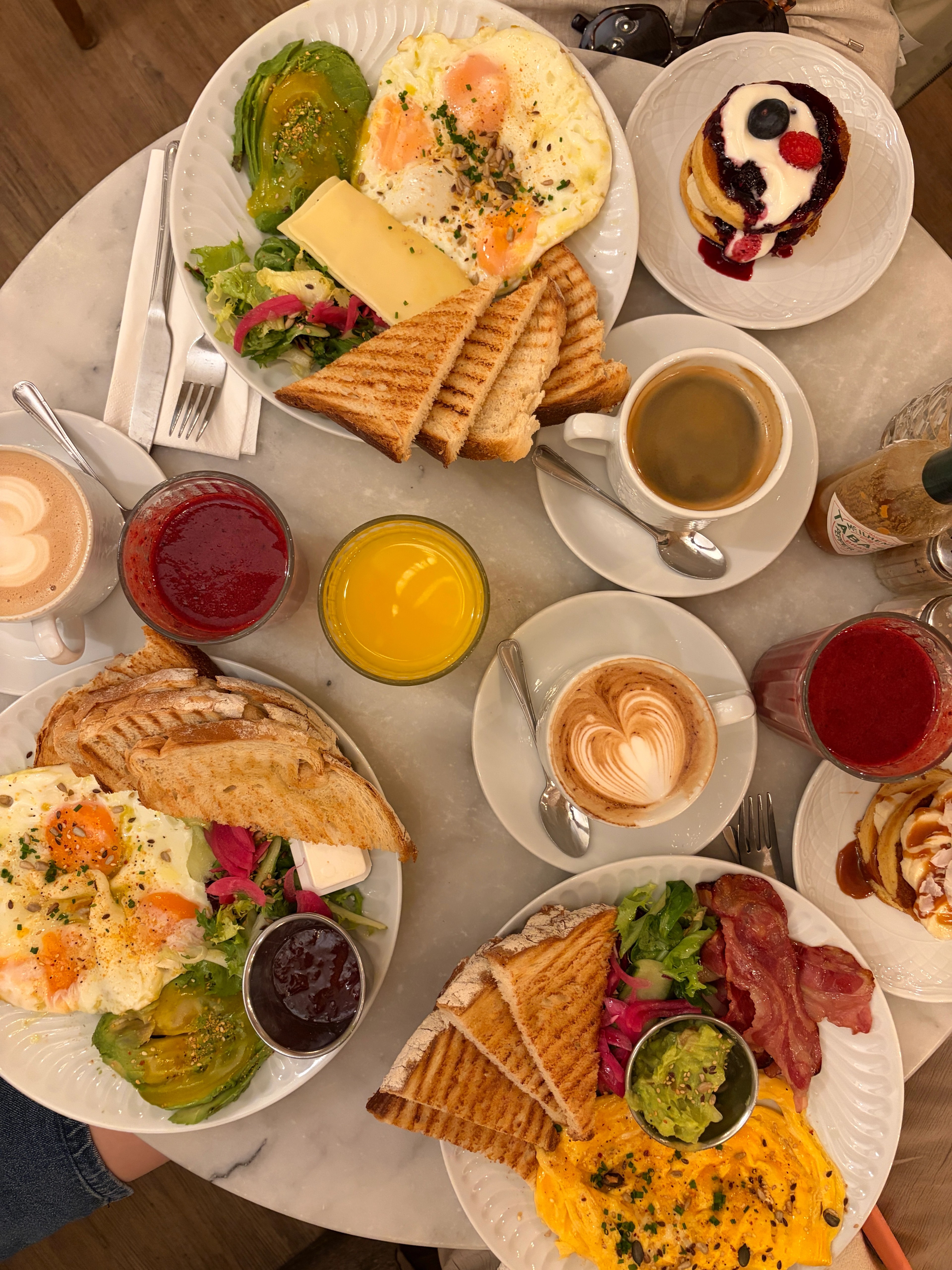 A picture of a table with brunch on it including eggs avocado and coffee