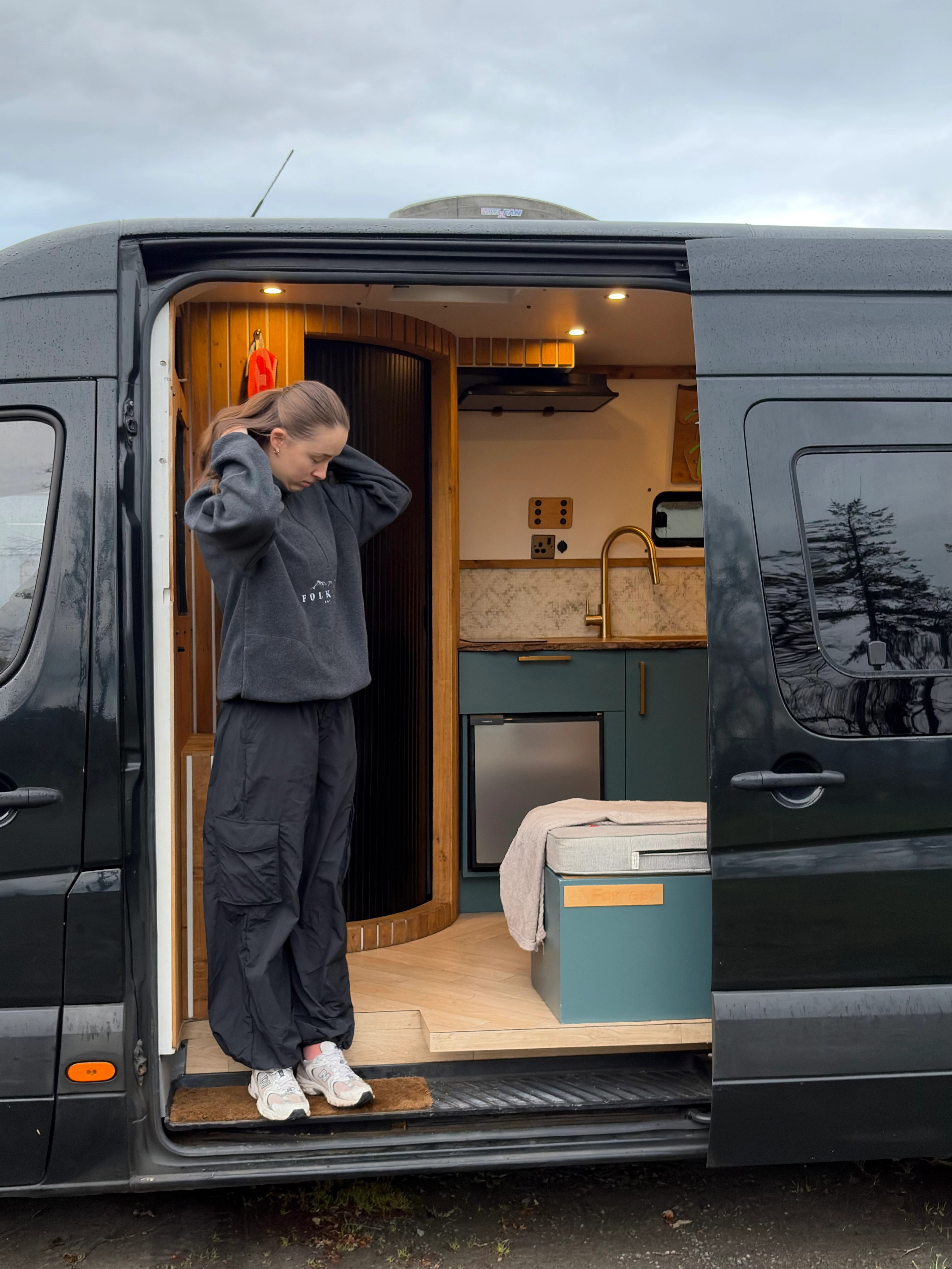 camperavan with the doors opening showing the inside with a girl standing at the entrance of the sliding door