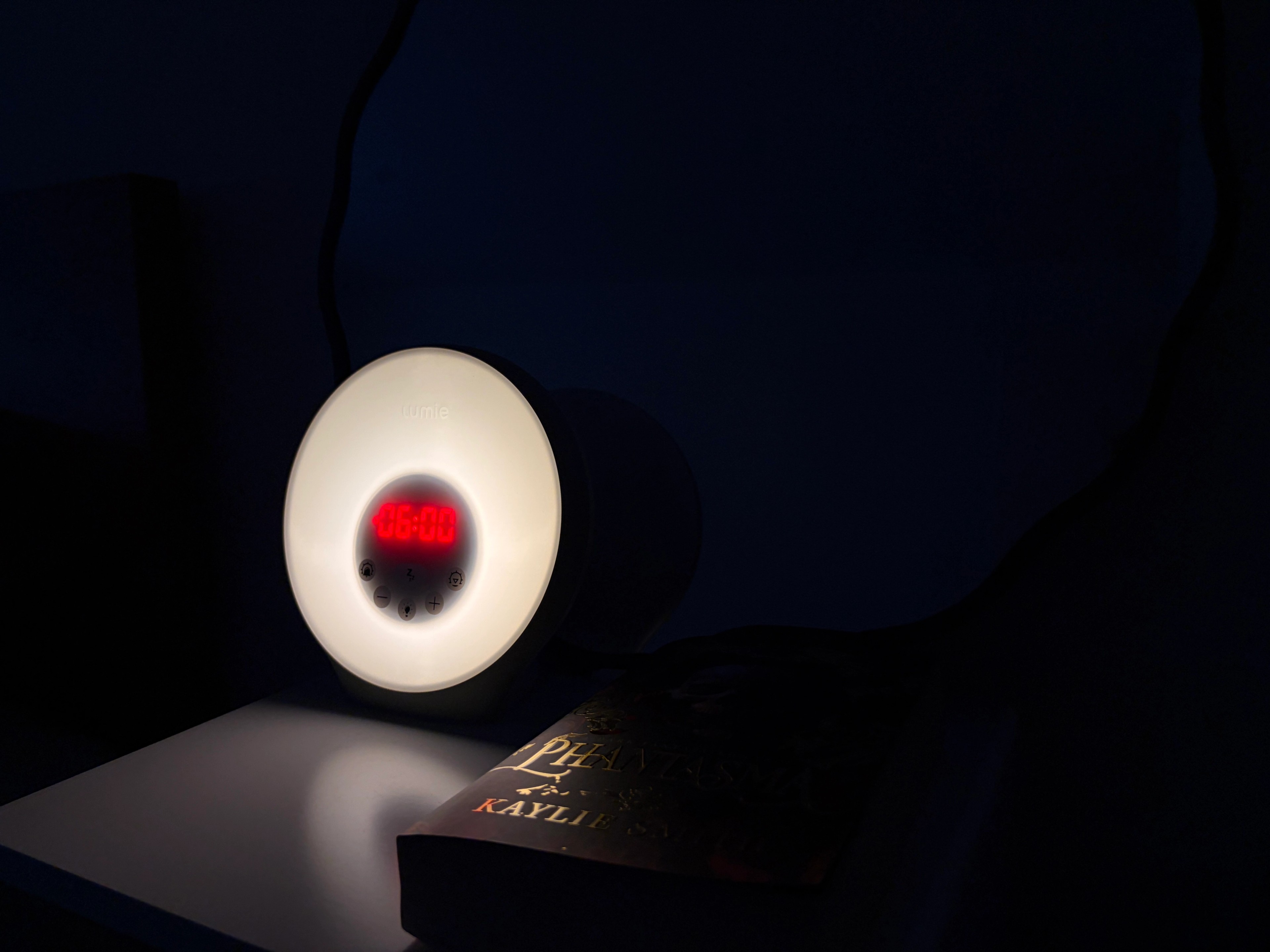 lumie alarm clock at night next to a bed