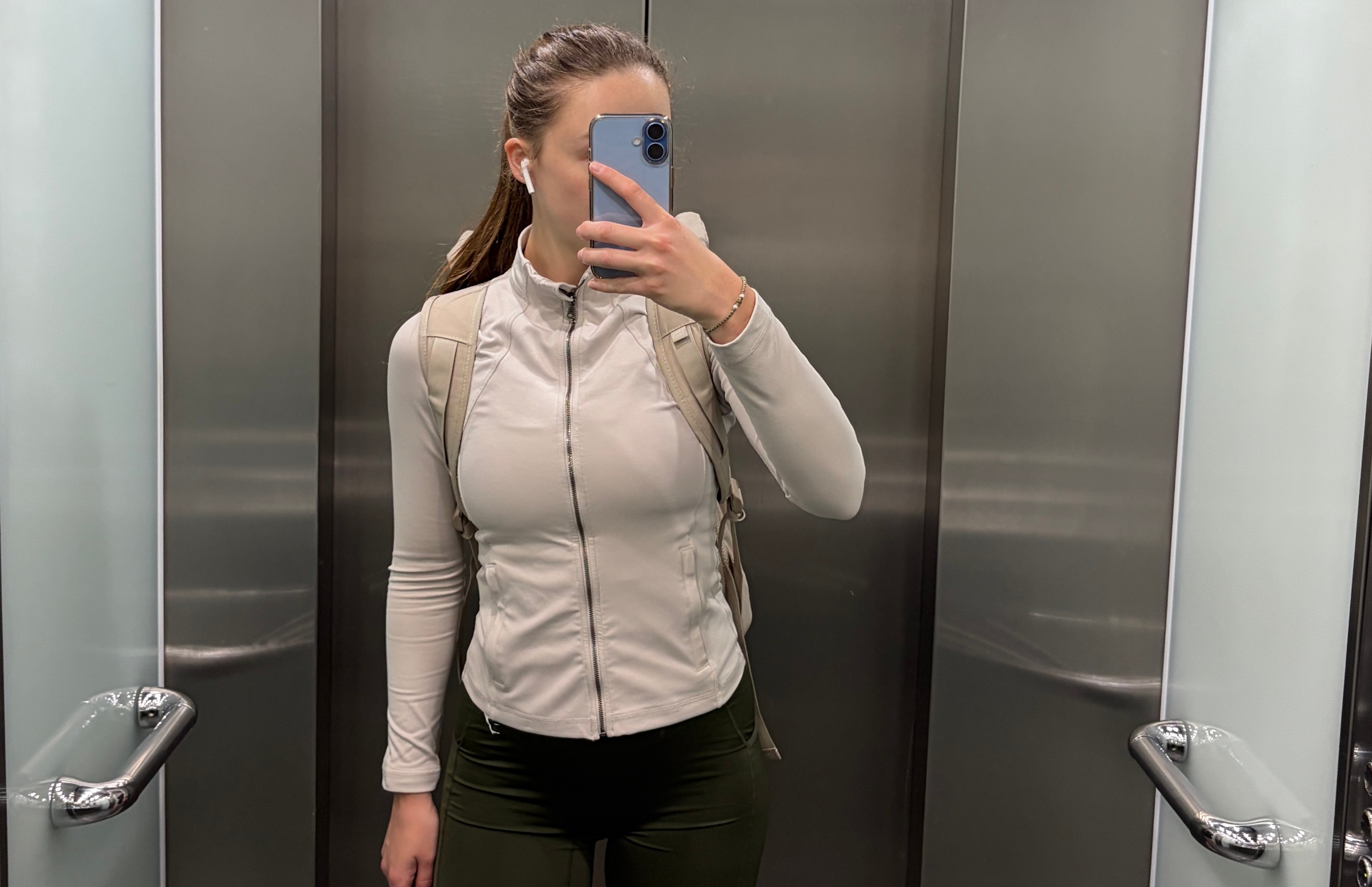 Woman in elevator taking a selfie in sports attire heading to the gym leaving the workplace 