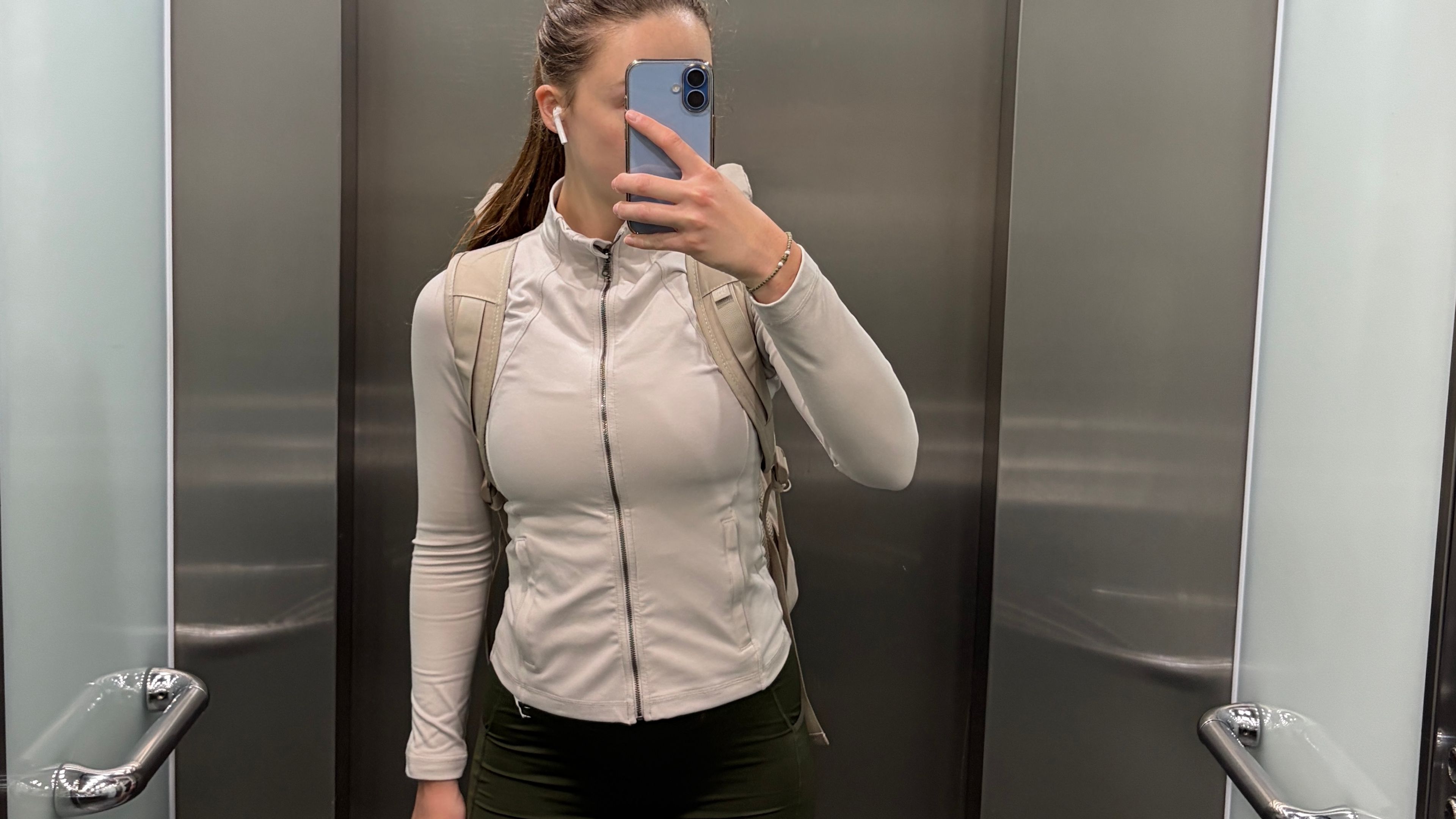 Woman in elevator taking a selfie in sports attire heading to the gym leaving the workplace