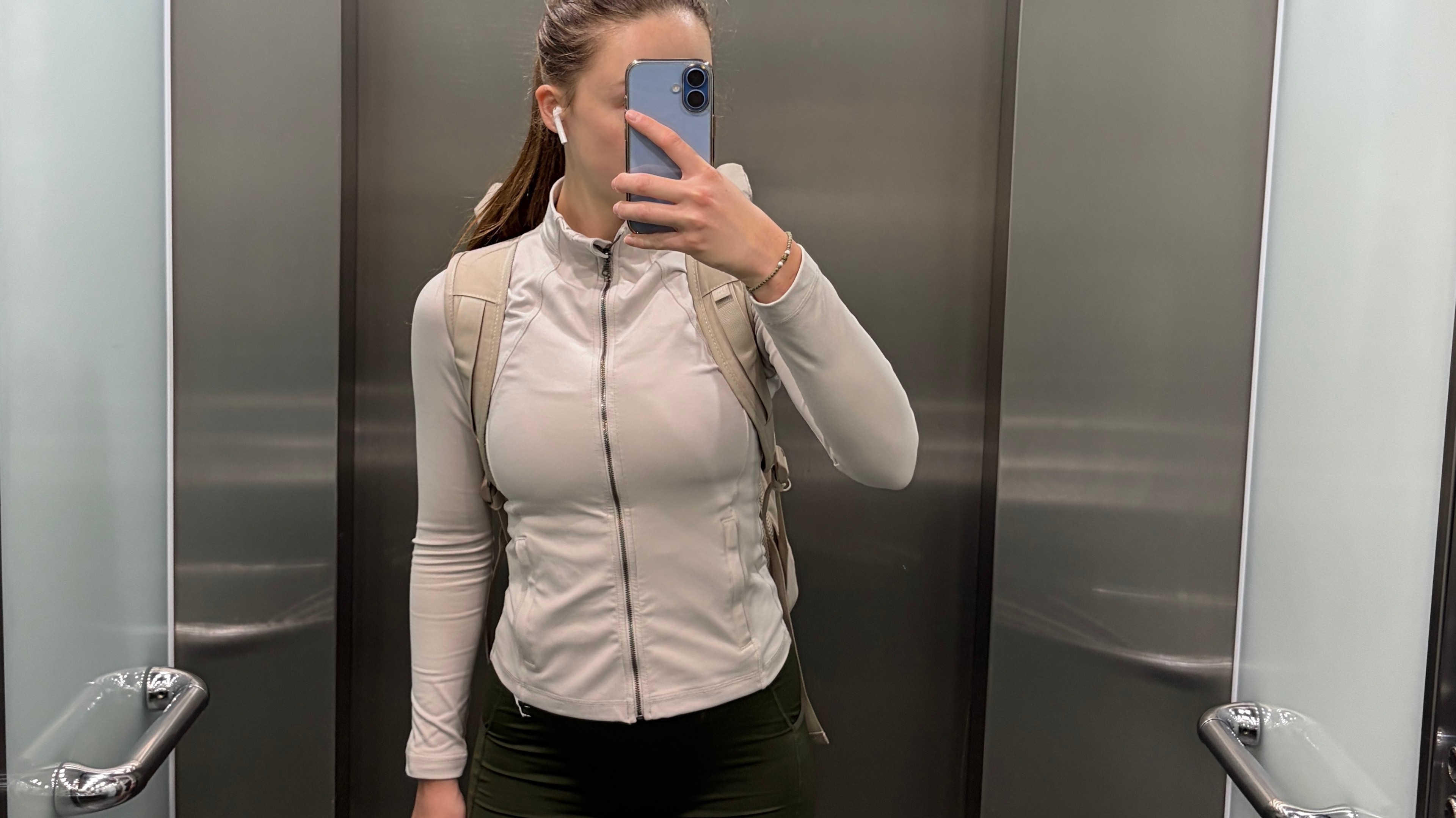 Woman in elevator taking a selfie in sports attire heading to the gym leaving the workplace