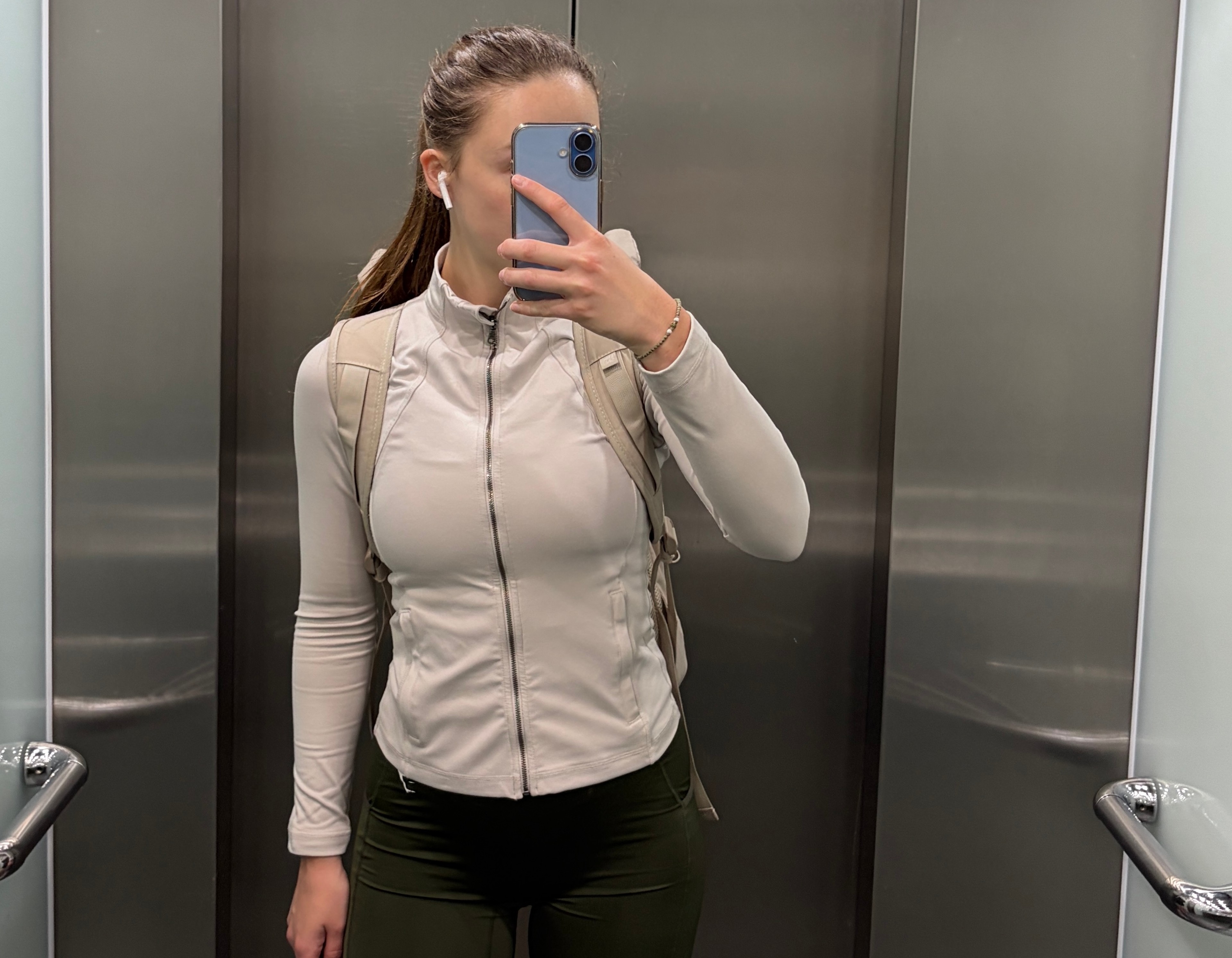 Woman in elevator taking a selfie in sports attire heading to the gym leaving the workplace