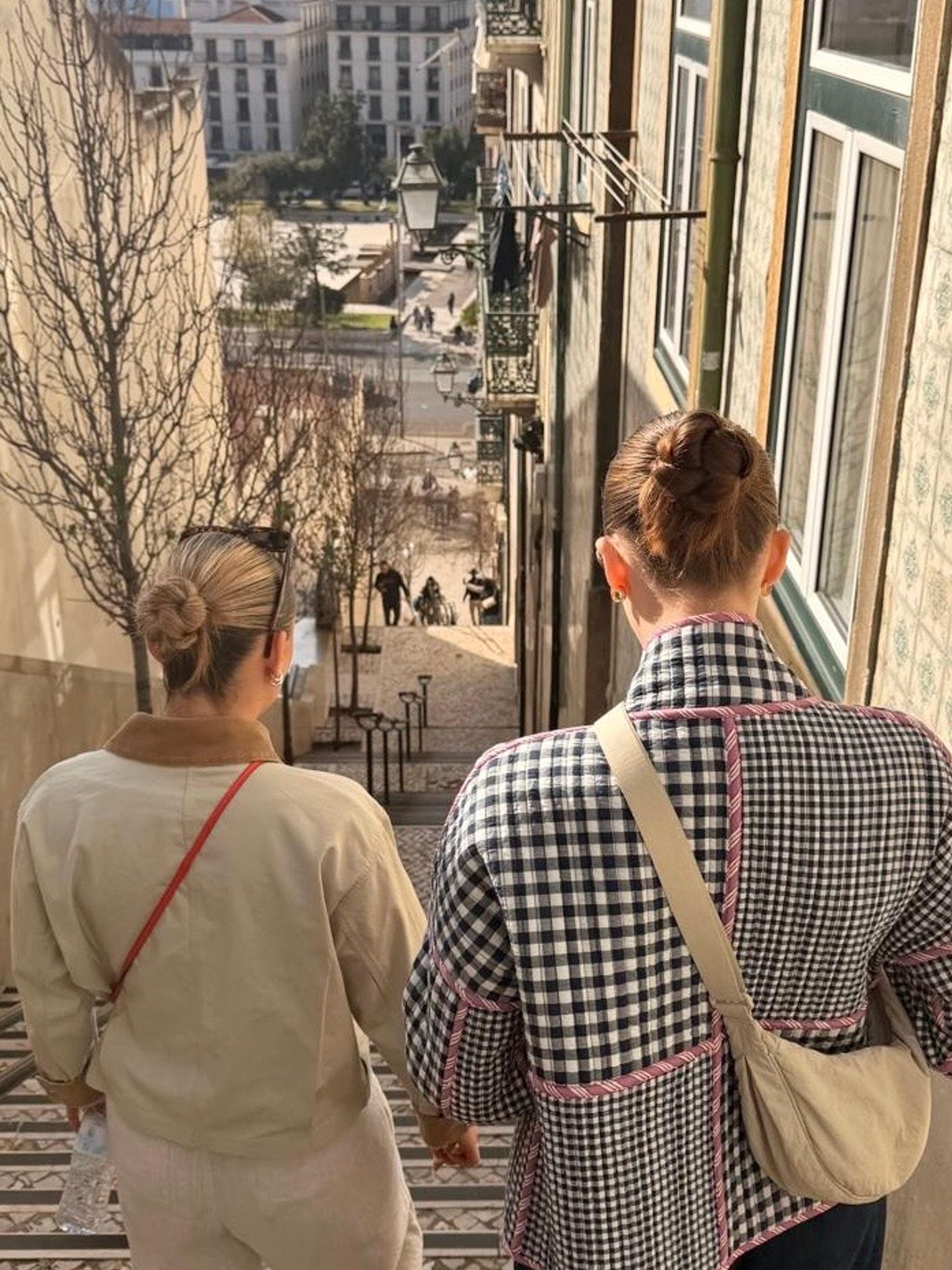Two girls walking with their hair in a bun in the streets of lisbon 