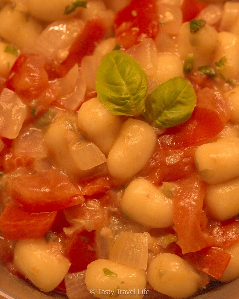 close-up van de pasta met pastasaus. Twee basilicumblaadjes bovenop.