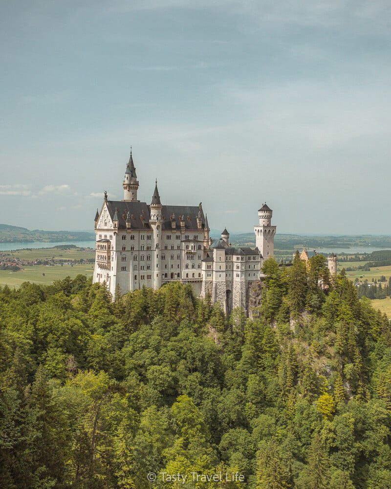 Neuschwanstein Fairytale castle on the hill with views of the land behind 