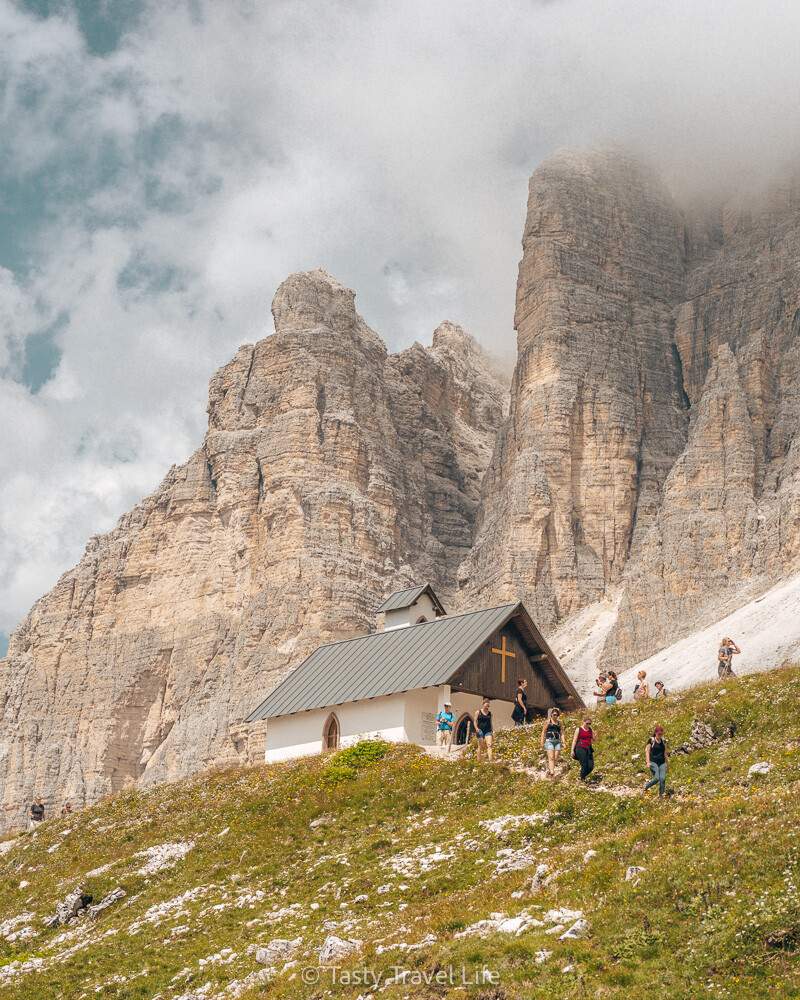 Small church in front of the mountain with clouds.