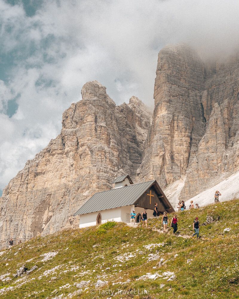 Petite église devant la montagne avec des nuages.