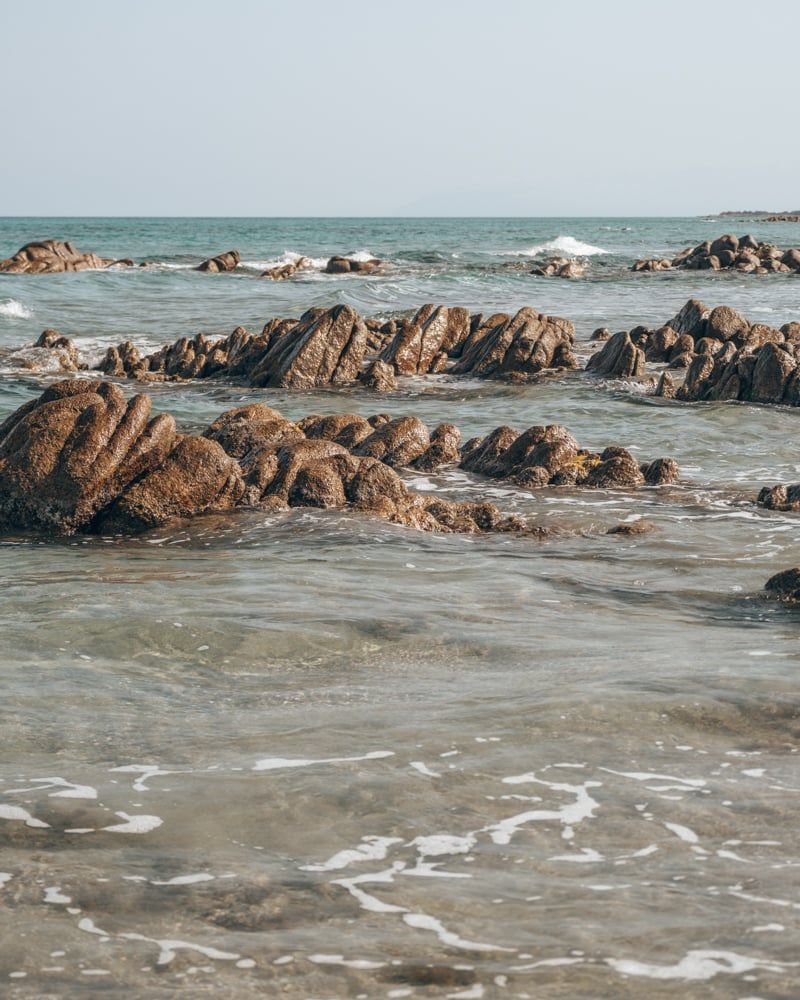 Kristalhelder water en rotsen bij het strand van Berchida