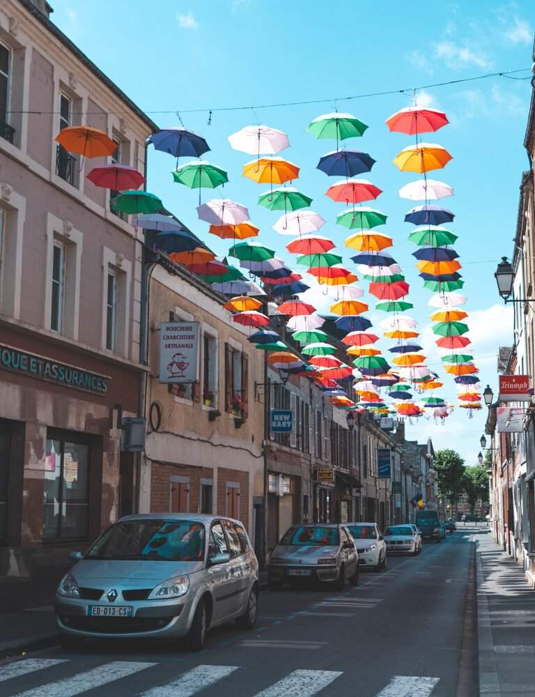 Rue centrale de Givet avec des parapluies colorés au-dessus
