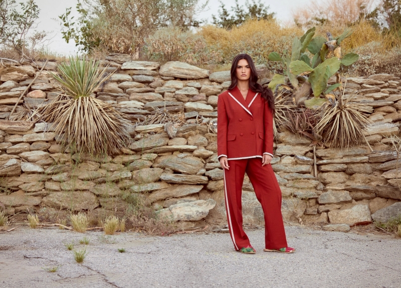 Model in a lace trimmed rust suit in front of a desert landscape
