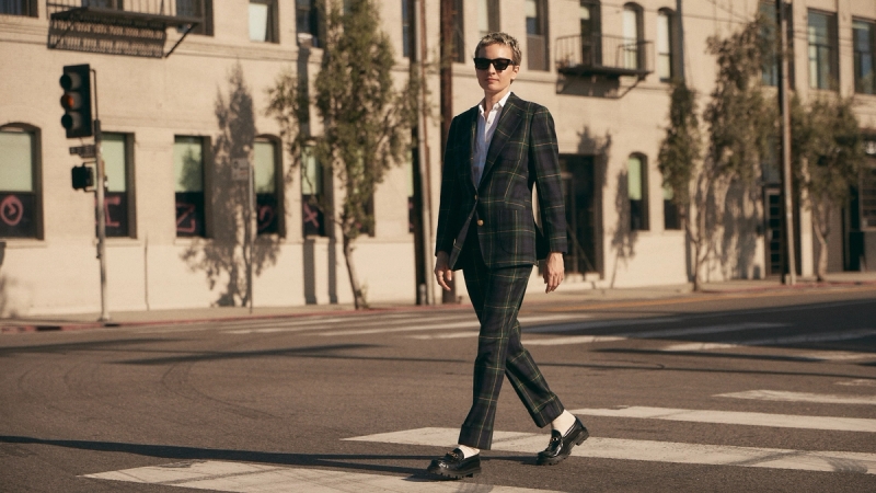 Model in a plaid custom suit, white socks and black loafers crosses the street in a crosswalk