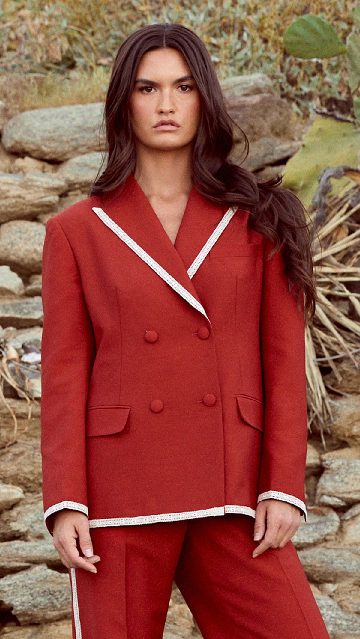 Model in a lace trimmed rust suit in front of a desert landscape