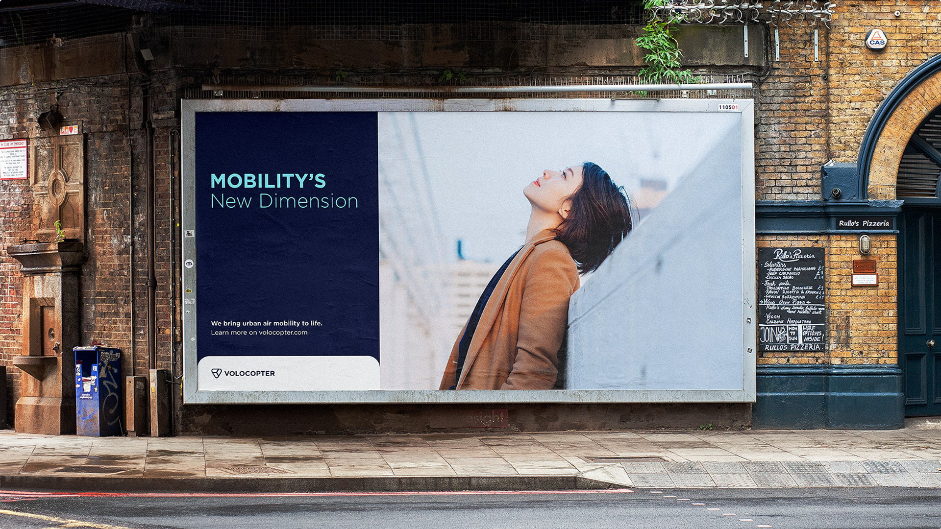 Kampagnenmotiv an Hauswand: „Mobility's New Dimension" – Frau blickt nach oben, geteiltes Layout dunkelblau/hell