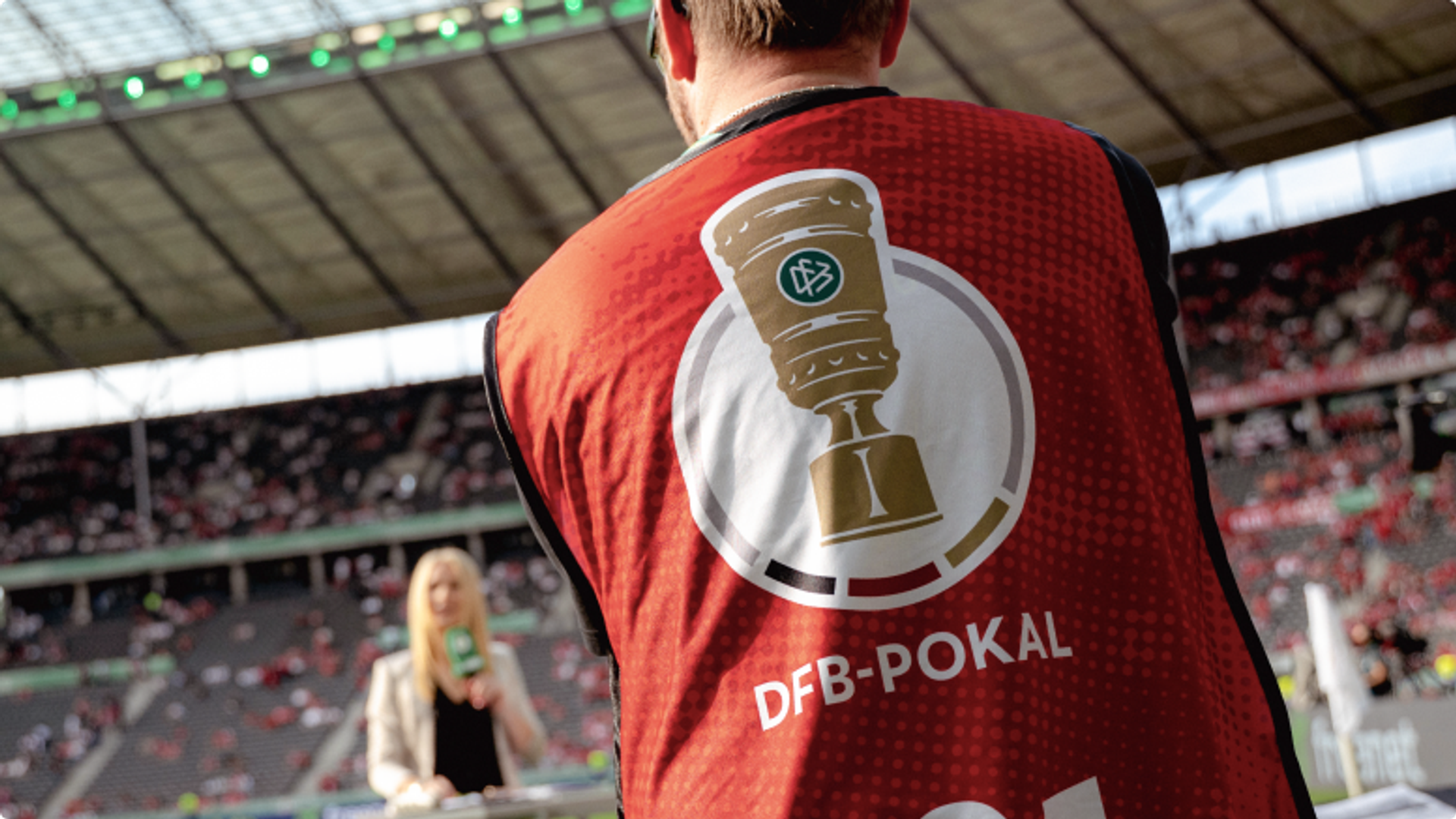 Rückenansicht einer Redaktionsweste im Stadion mit DFB-Pokal-Logo und dem Schriftzug DFB-Pokal.