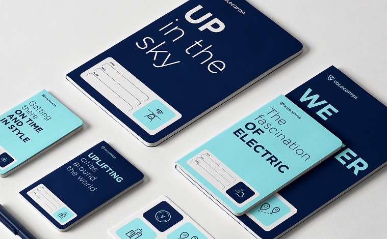 Volocopter Notizbuch-Mockups in Dunkelblau und Hellblau mit Slogans „Up in the sky" und „The fascination of electric"