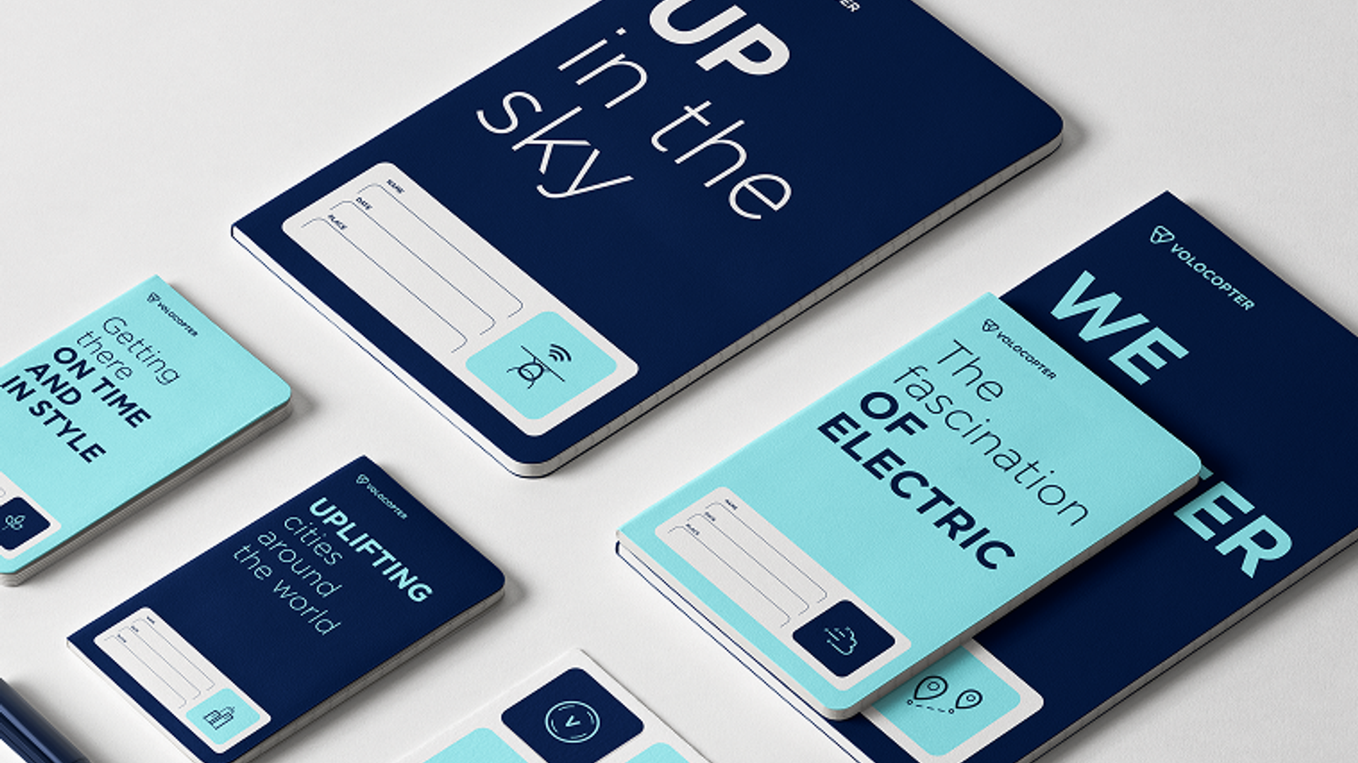 Volocopter Notizbuch-Mockups in Dunkelblau und Hellblau mit Slogans „Up in the sky" und „The fascination of electric"