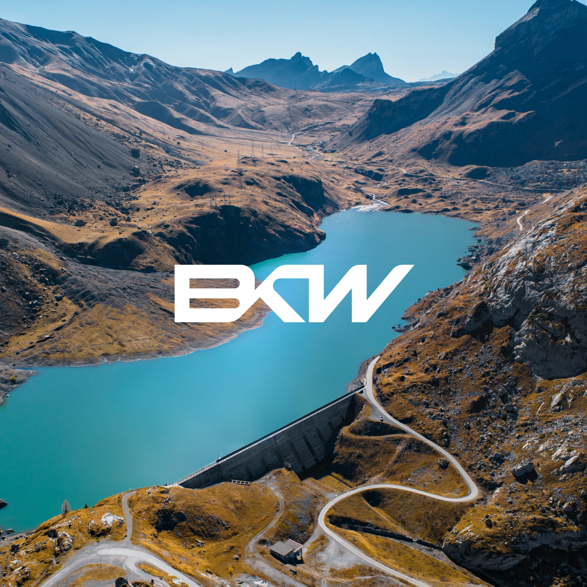 BKW Logo in Weiß vor einer Luftaufnahme einer Staumauer mit Stausee.