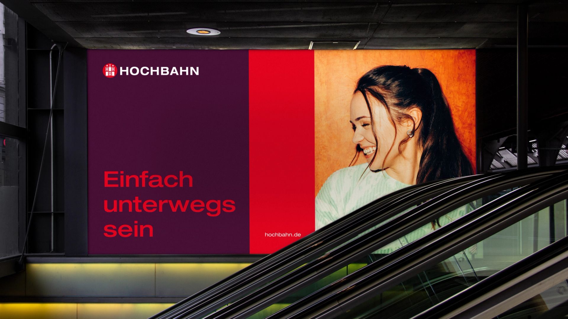 Kampagnenmotiv der Hochbahn an einer Rolltreppe: Frau lächelt, links Logo und Claim „Einfach unterwegs sein" auf Rot und Dunkelviolett.