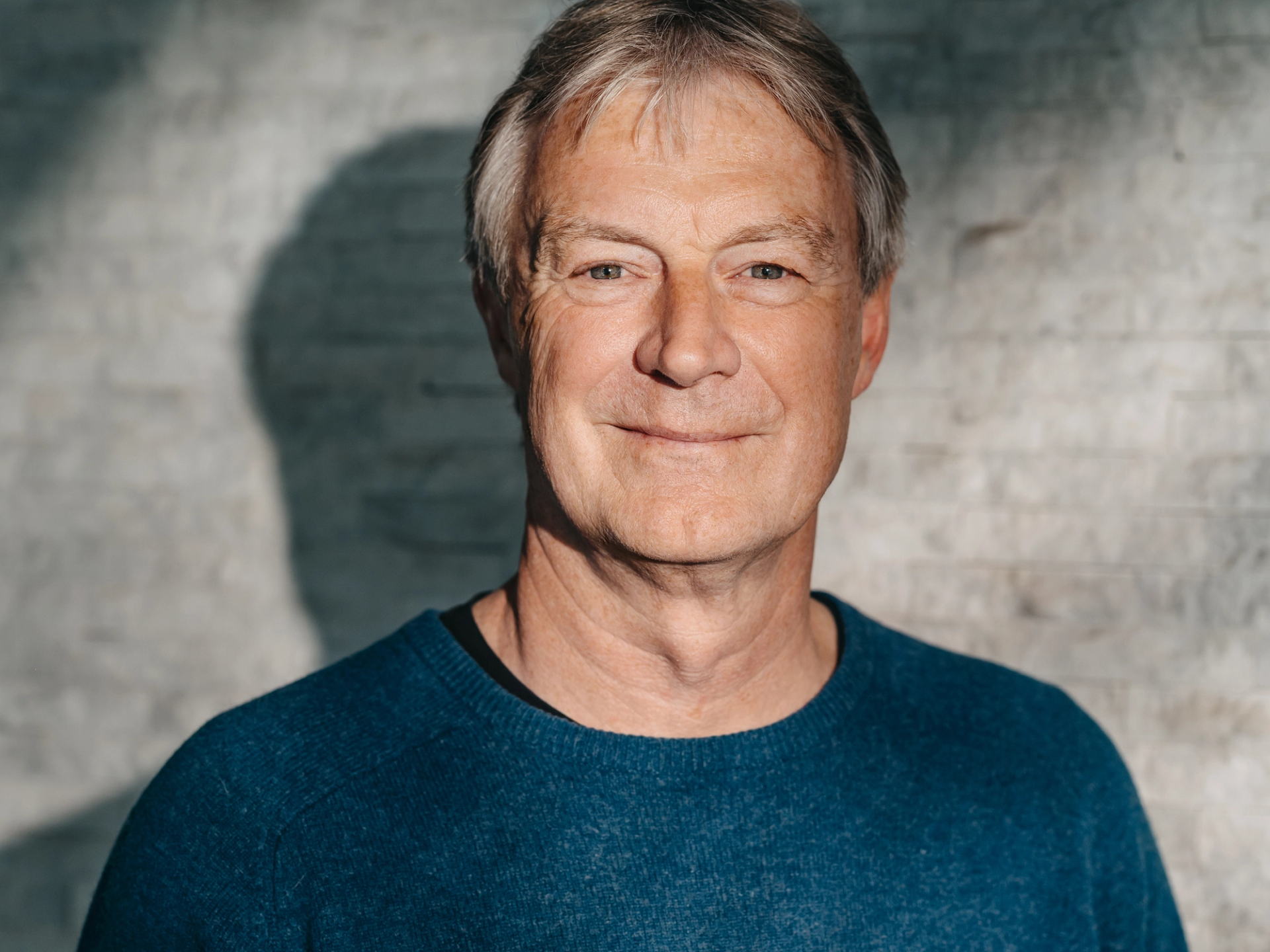 Hannes Müller, Portraitfoto, mit kurzen ergrauten Haaren, lächelt freundlich in die Kamera.