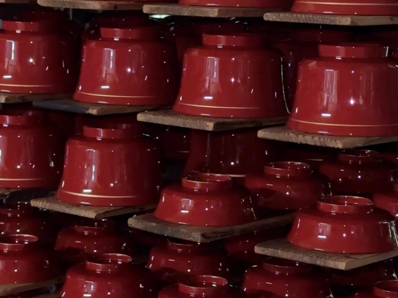 Red lacquer bowls aligned on a rack with a gold line