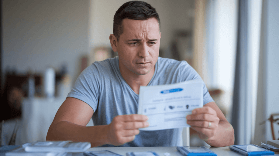 A man sits at a table reading the instructions to a rapid self-test