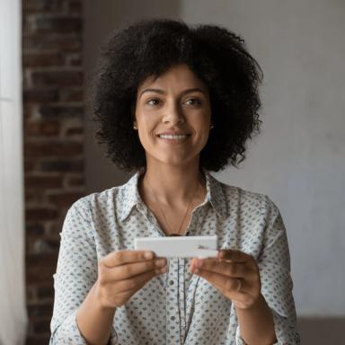 A woman reads home heath test results against a grey wall