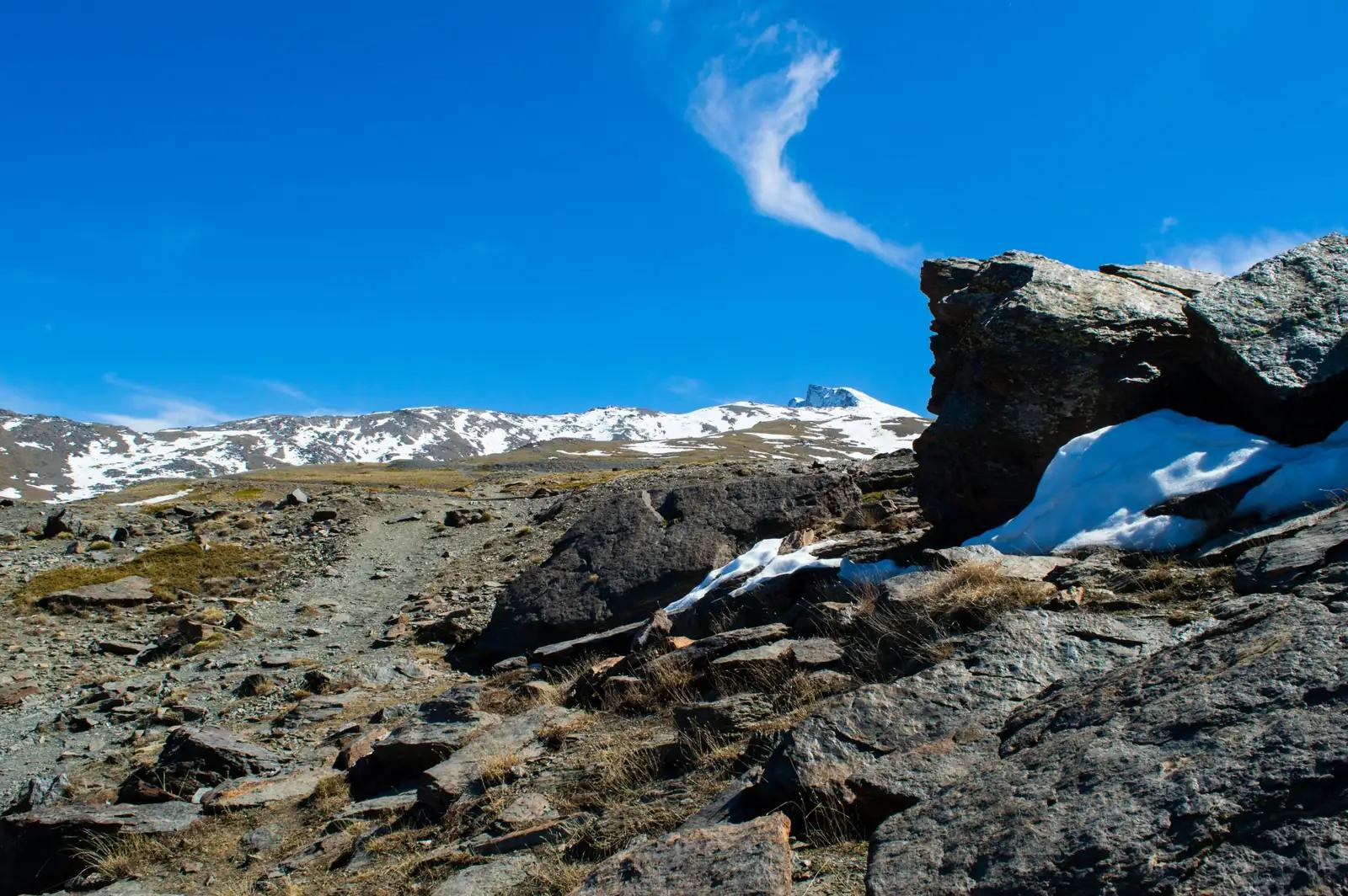 Rocky path with patches of snow leading towards the summit of Pico Veleta, Sierra Nevada, Spain