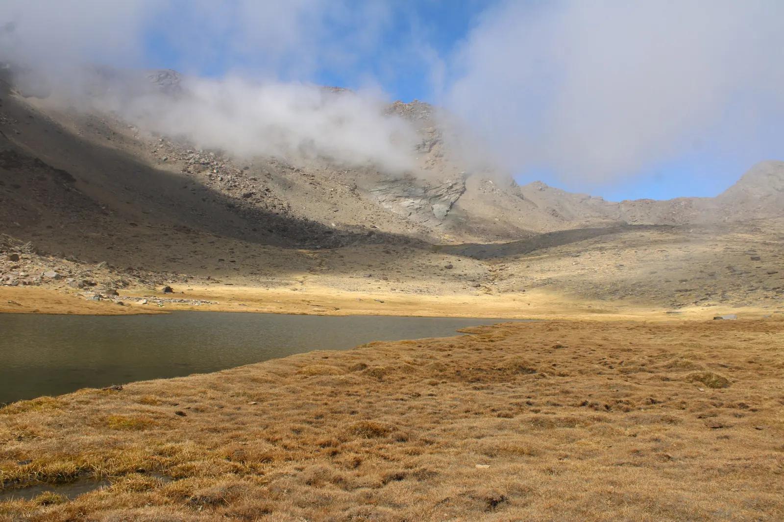 Laguna de la Caldera, a high mountain lake below Mulhacén under drifting cloud, Sierra Nevada National Park, Spain