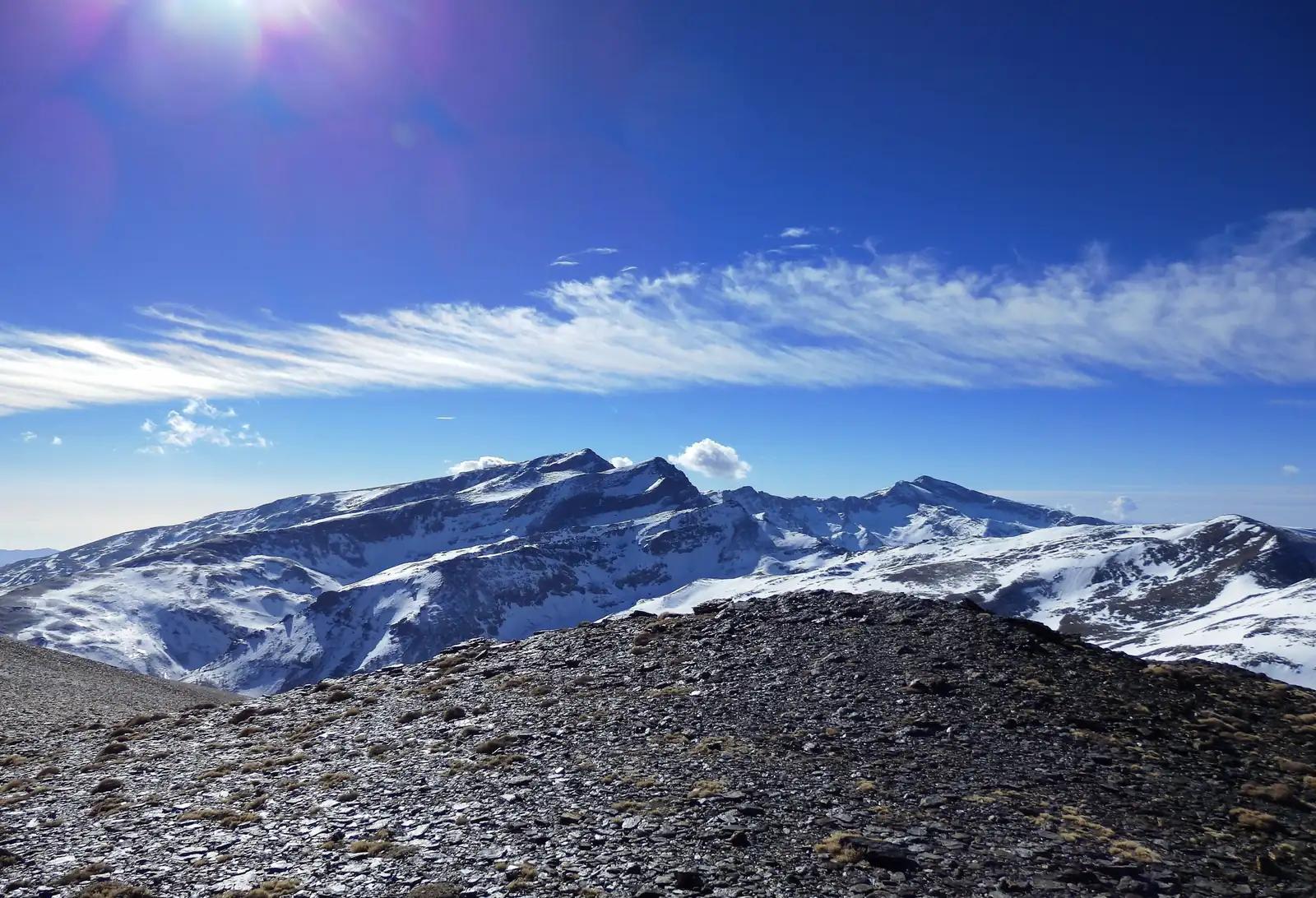 Snowy peaks from a rocky ridge on Mulhacén, the highest summit for hiking in Sierra Nevada, Spain