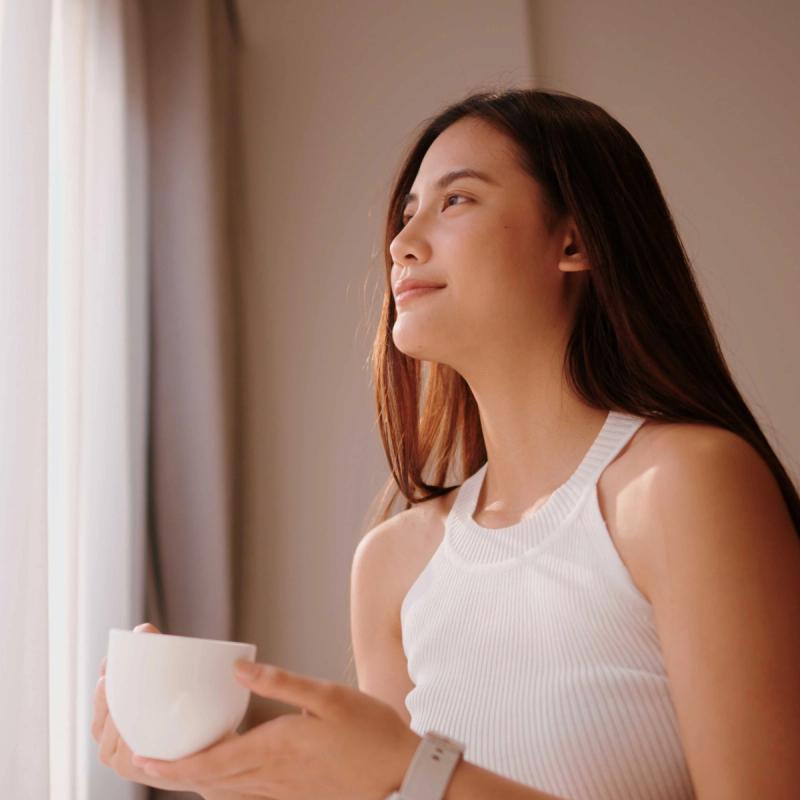 Smiling woman holding a mug and looking out the window