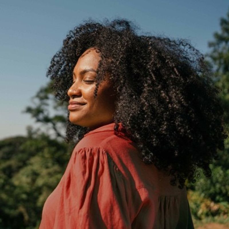women outside with face looking towards sun and smile on her face