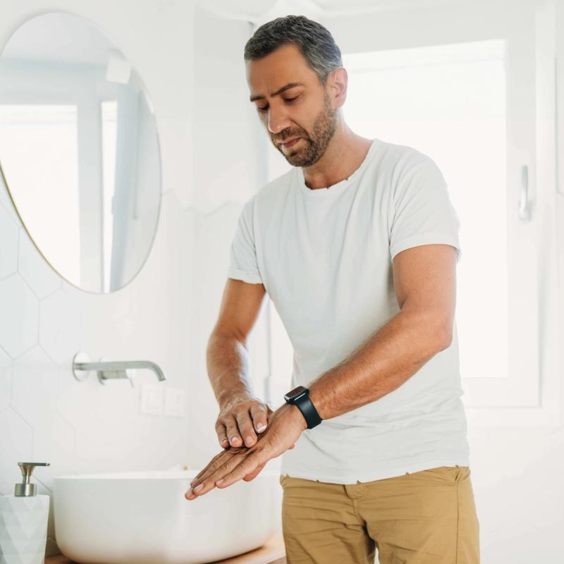 Image of man applying cream to his hand to treat scabies or body lice rash.