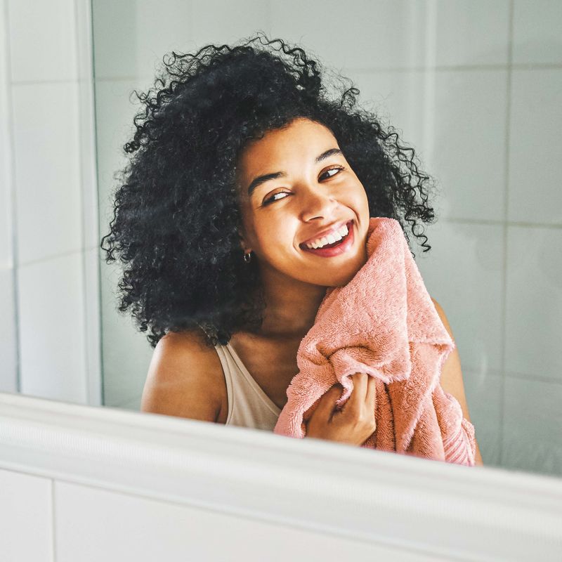 Women Looking in Mirror Wiping Face Off With a Towel