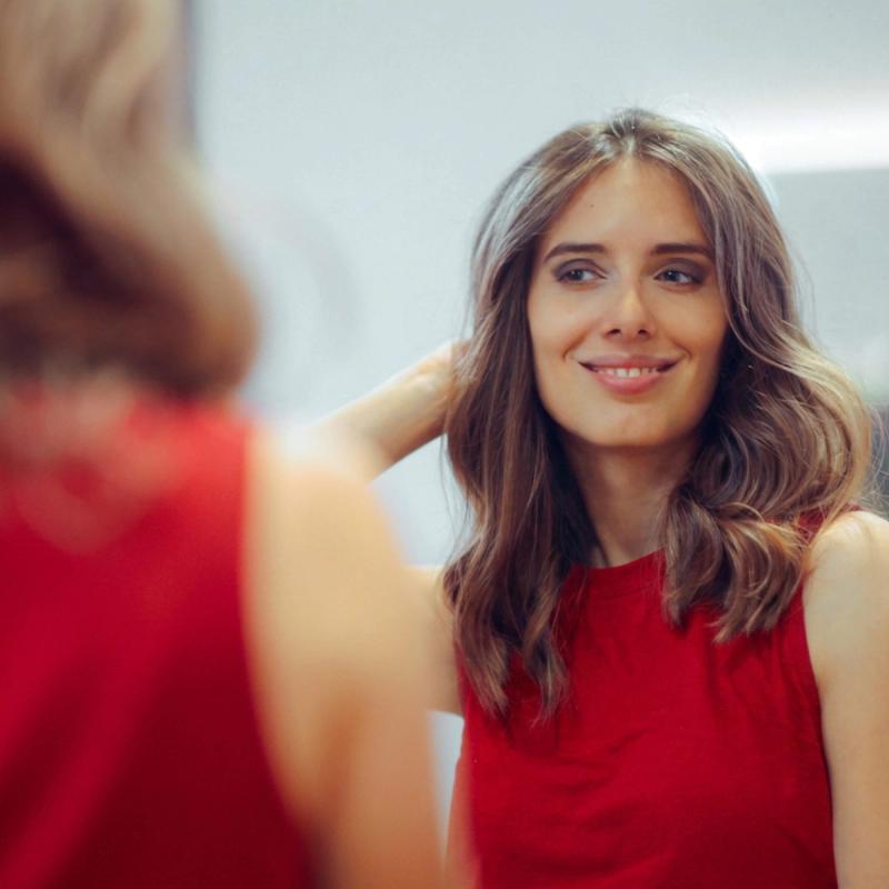 Confident woman admiring her hair in the mirror.