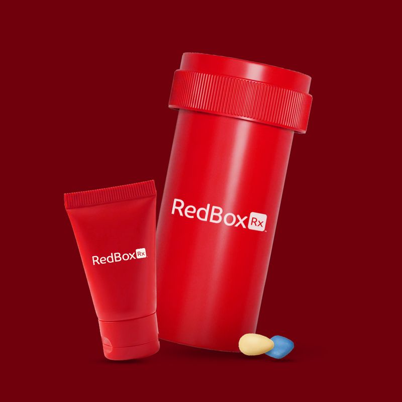 White prescription pill bottle labeled “RedBox Rx” on a bedside table next to a glass of water.