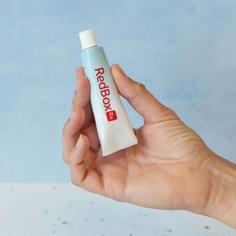 Hand holding RedBox Rx medicated cream in bathroom