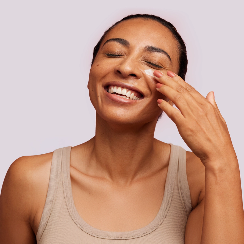 A smiling woman applying prescription acne cream