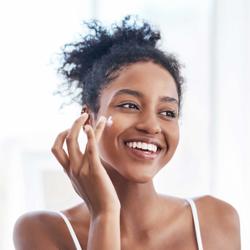 Smiling Woman Applying Hydroquinone Cream to Cheek
