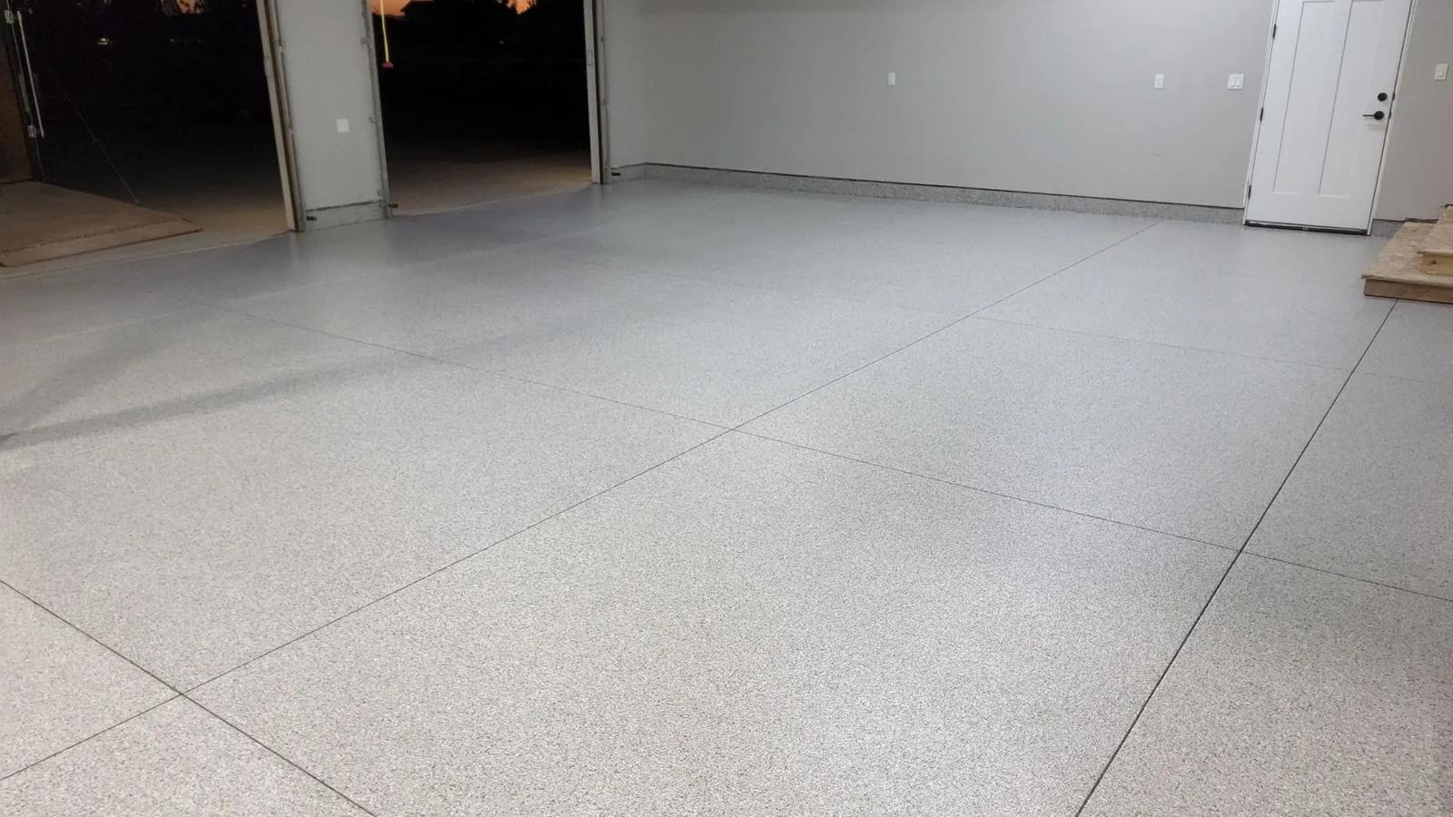 A newly coated gray garage floor in Boise with both bays open at sunset.