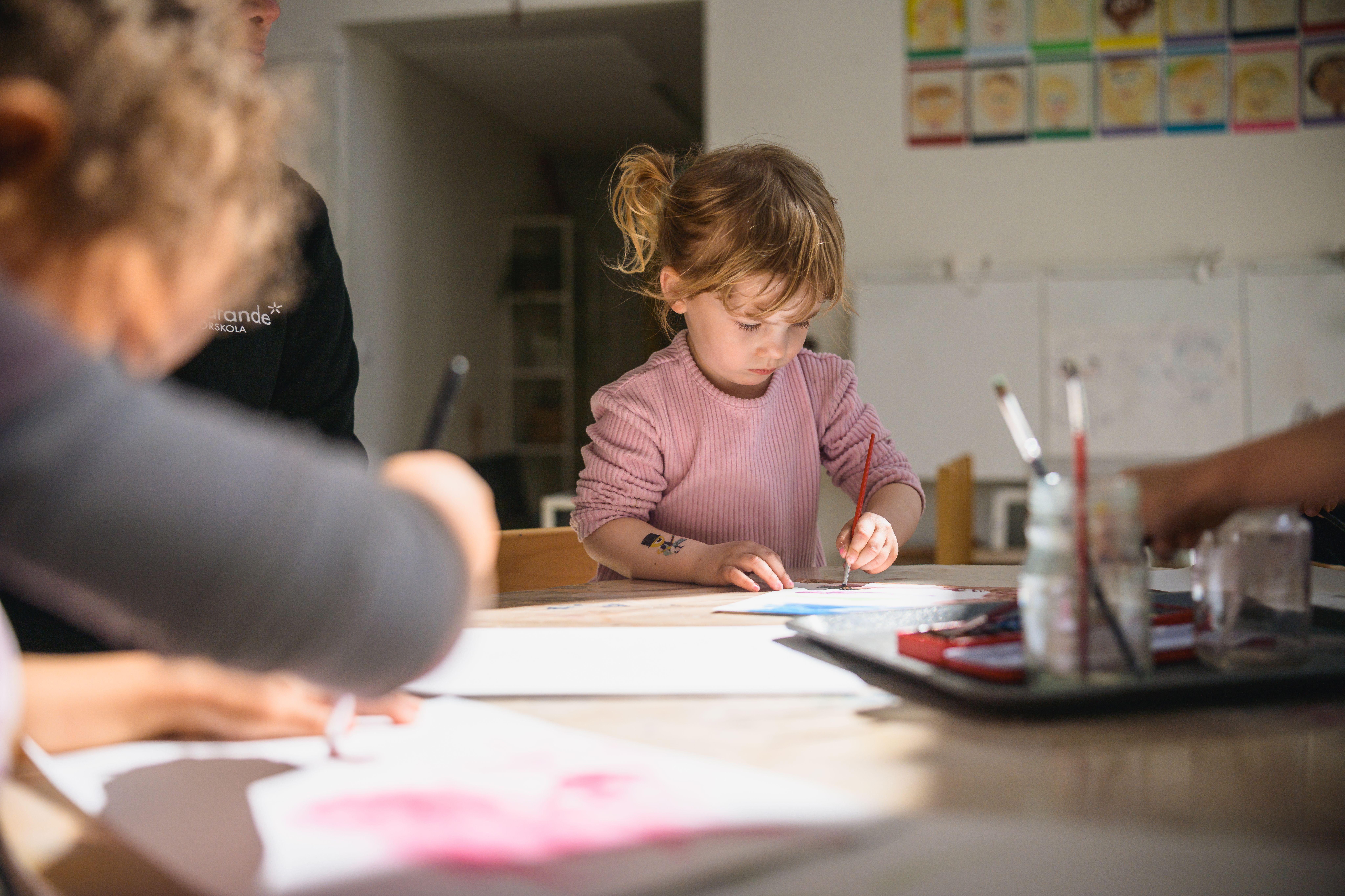 Pedagog sitter med barn och ritar vid ett bord