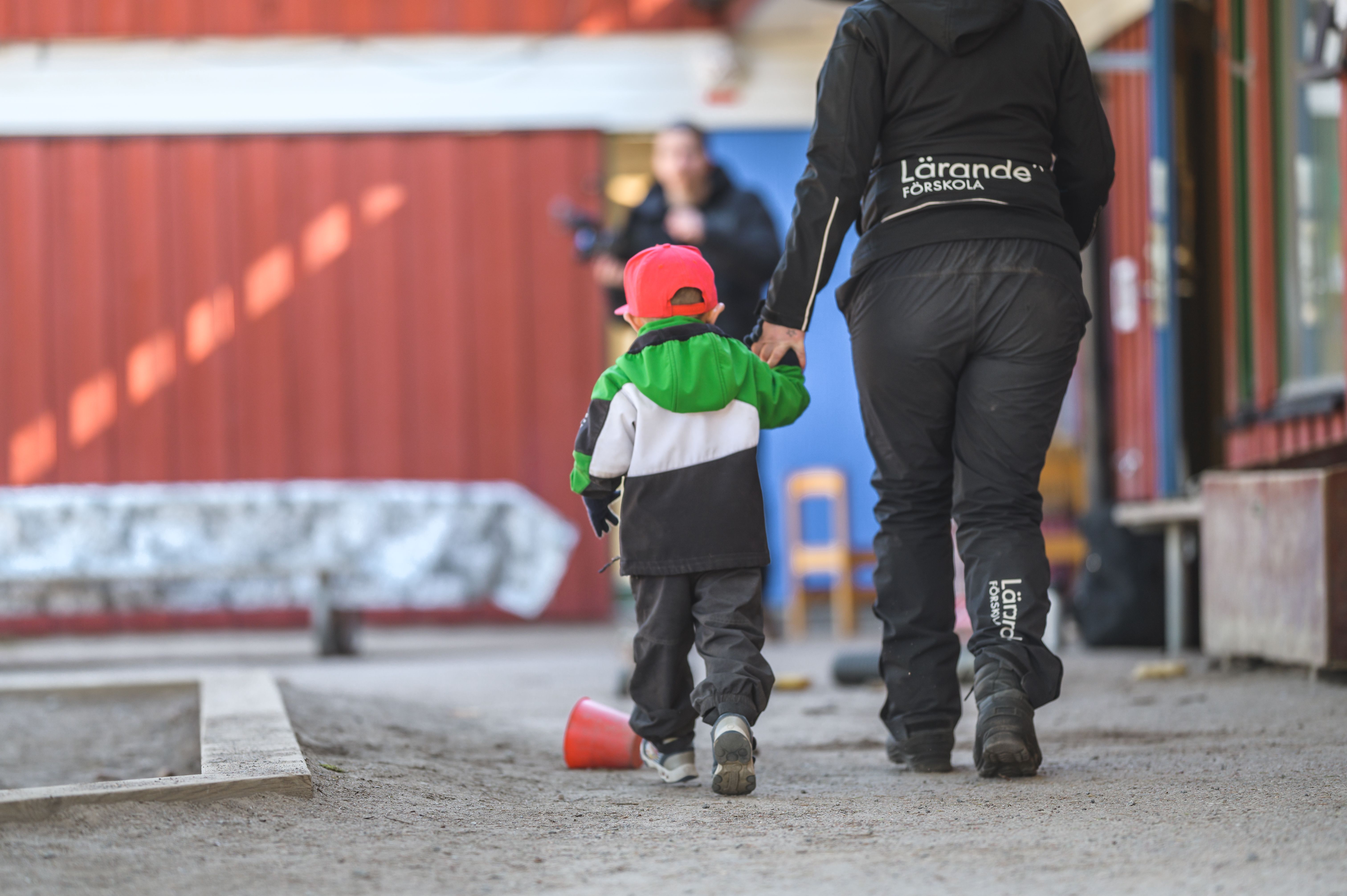 Barn går med pedagog på gården