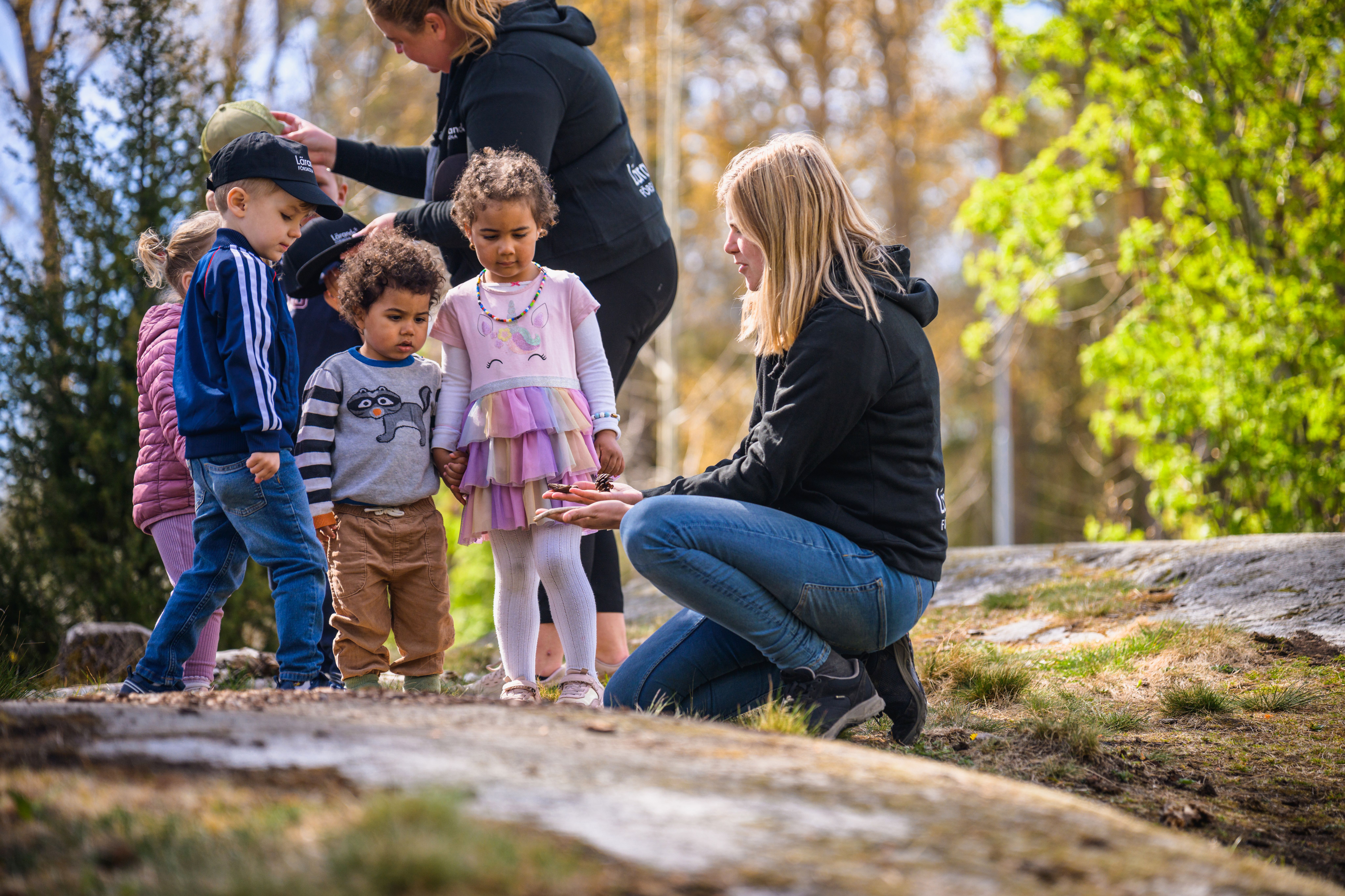 Pedagog med barngrupp som kollar på kottar