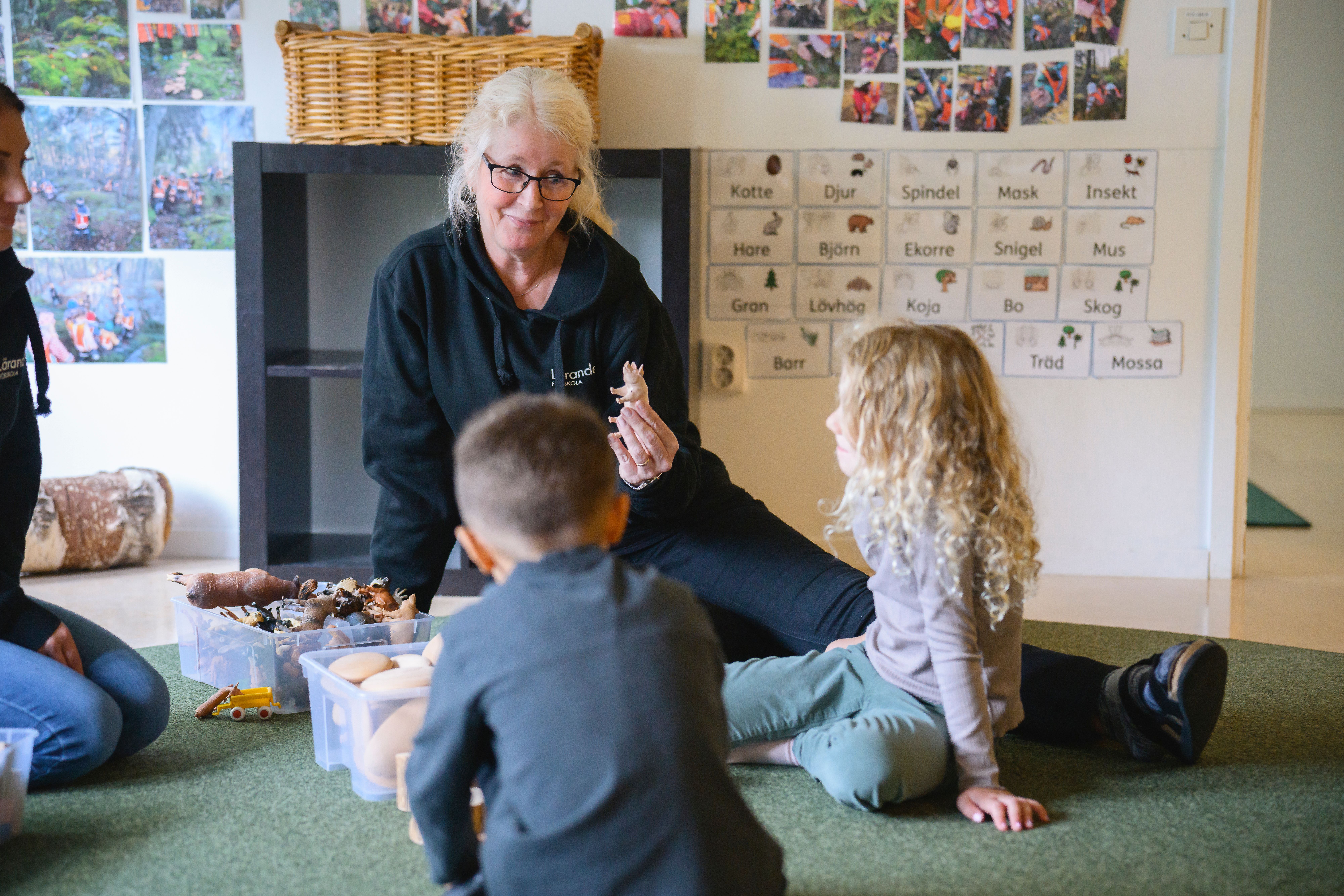 pedagog utomhus med tre barn som målar på staffli