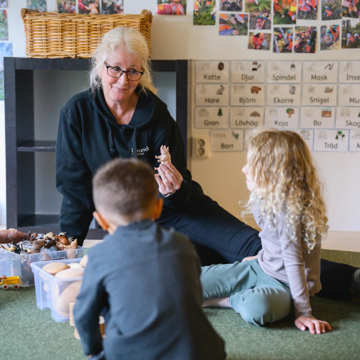 pedagog utomhus med tre barn som målar på staffli