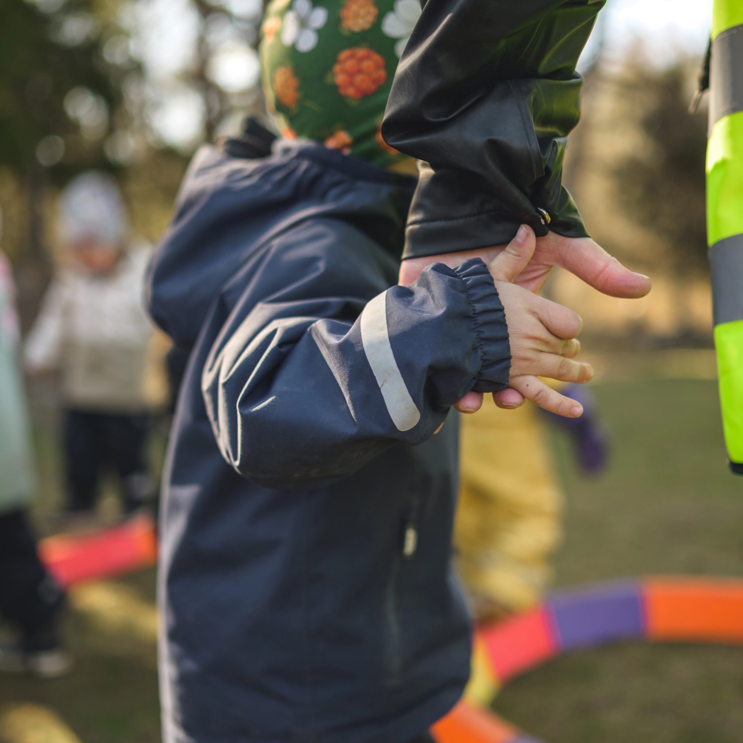 Barn håller pedagog i handen utomshus